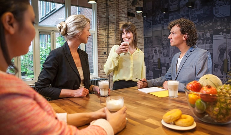 Personen trinken Kaffee aus JDE-Kaffeemaschine im Aufenthaltsraum