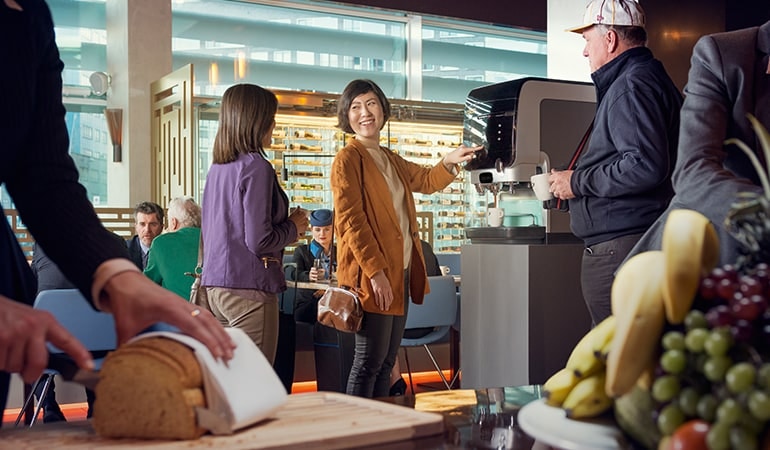 Personen in einem Café bedienen sich in Selbstbedienung an Jacobs-Kaffeemaschine